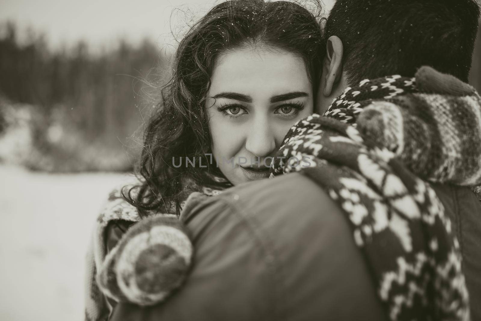 young man and woman stand kissing and hugging. bride and groom in love couple in knitted scarf and mittens in winter with snow and snowflakes. wedding dress. mexican people