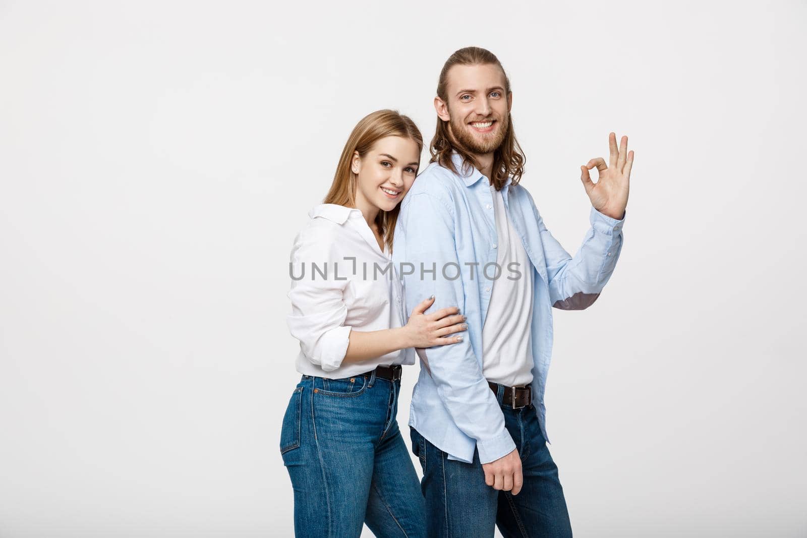 Happy young couple doing Ok gesture, isolated on white background.