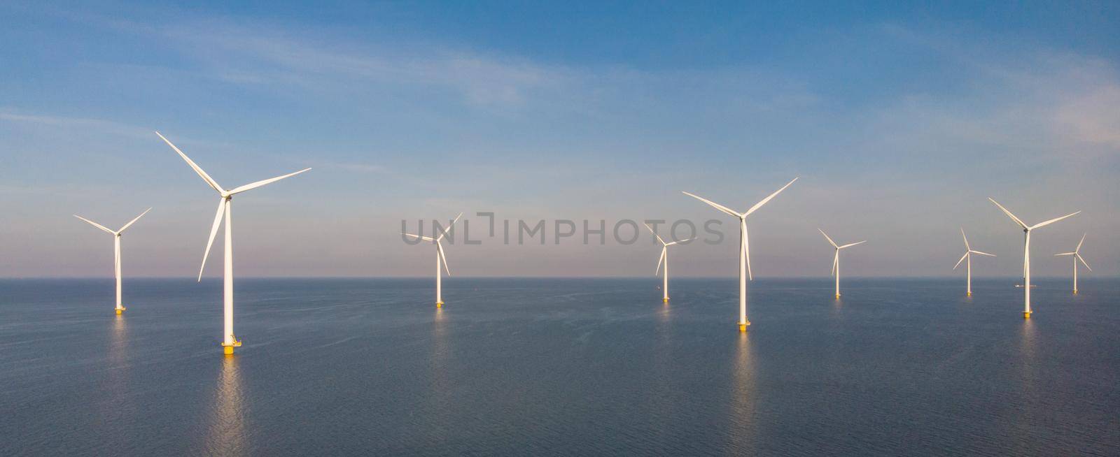 Huge windmill turbines, Offshore Windmill farm in the ocean Westermeerwind park , windmills isolated at sea on a beautiful bright day Netherlands Flevoland Noordoostpolder by fokkebok