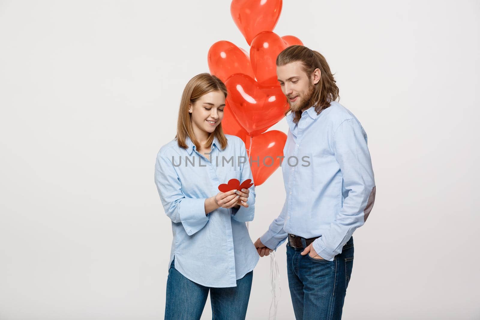 Young attactive caucasian couple holding heart balloon and paper