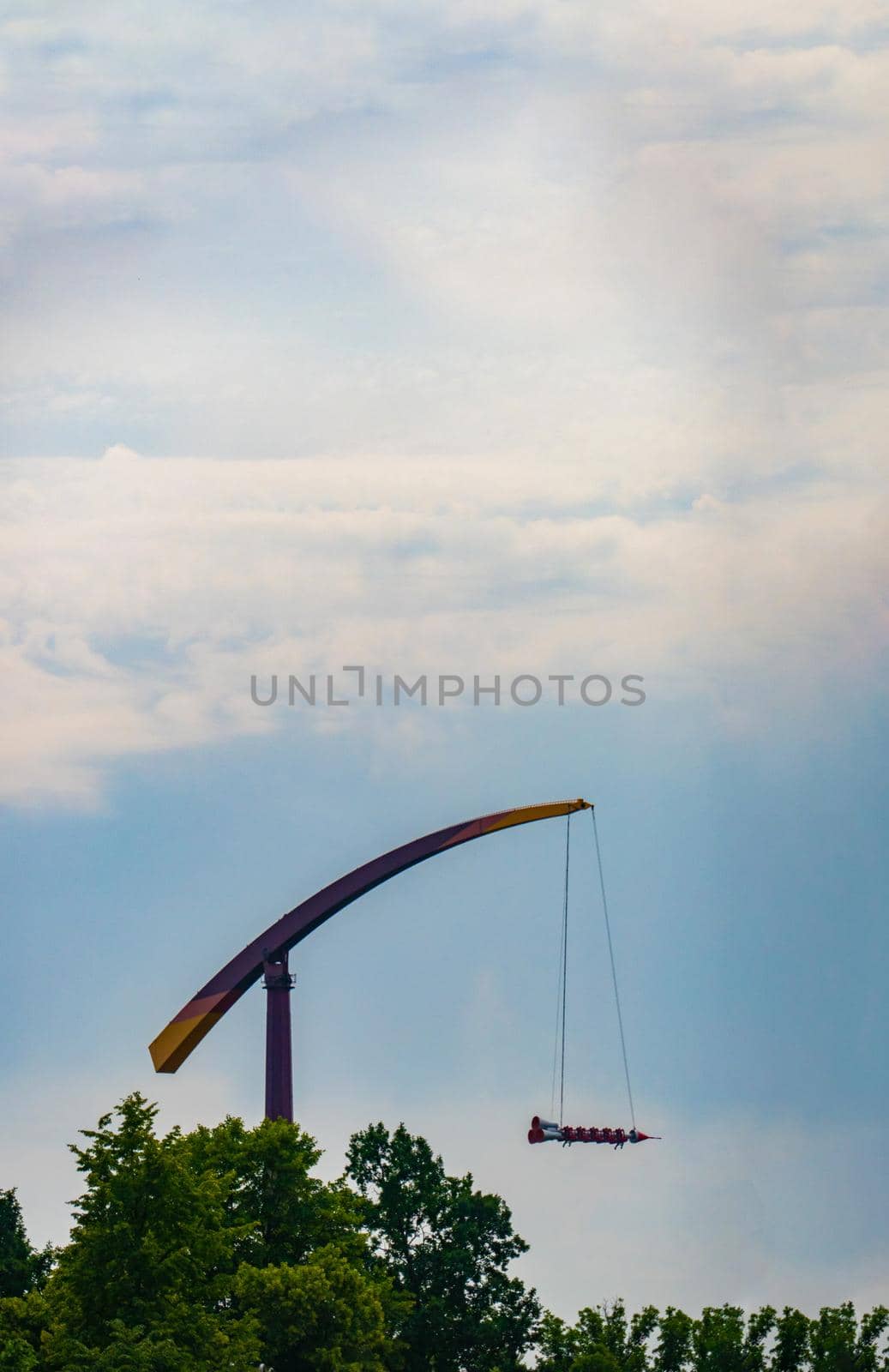 landscape of an amusement park with rocket rides attraction showing above the tree tops against a blue sky. banner with copy space