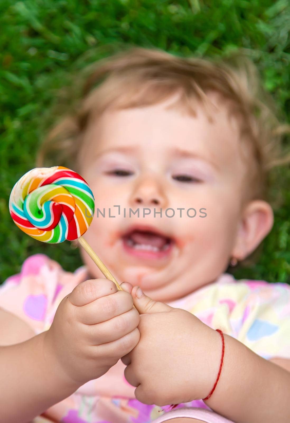 Baby eats a lollipop in the park. Selective focus. Child.
