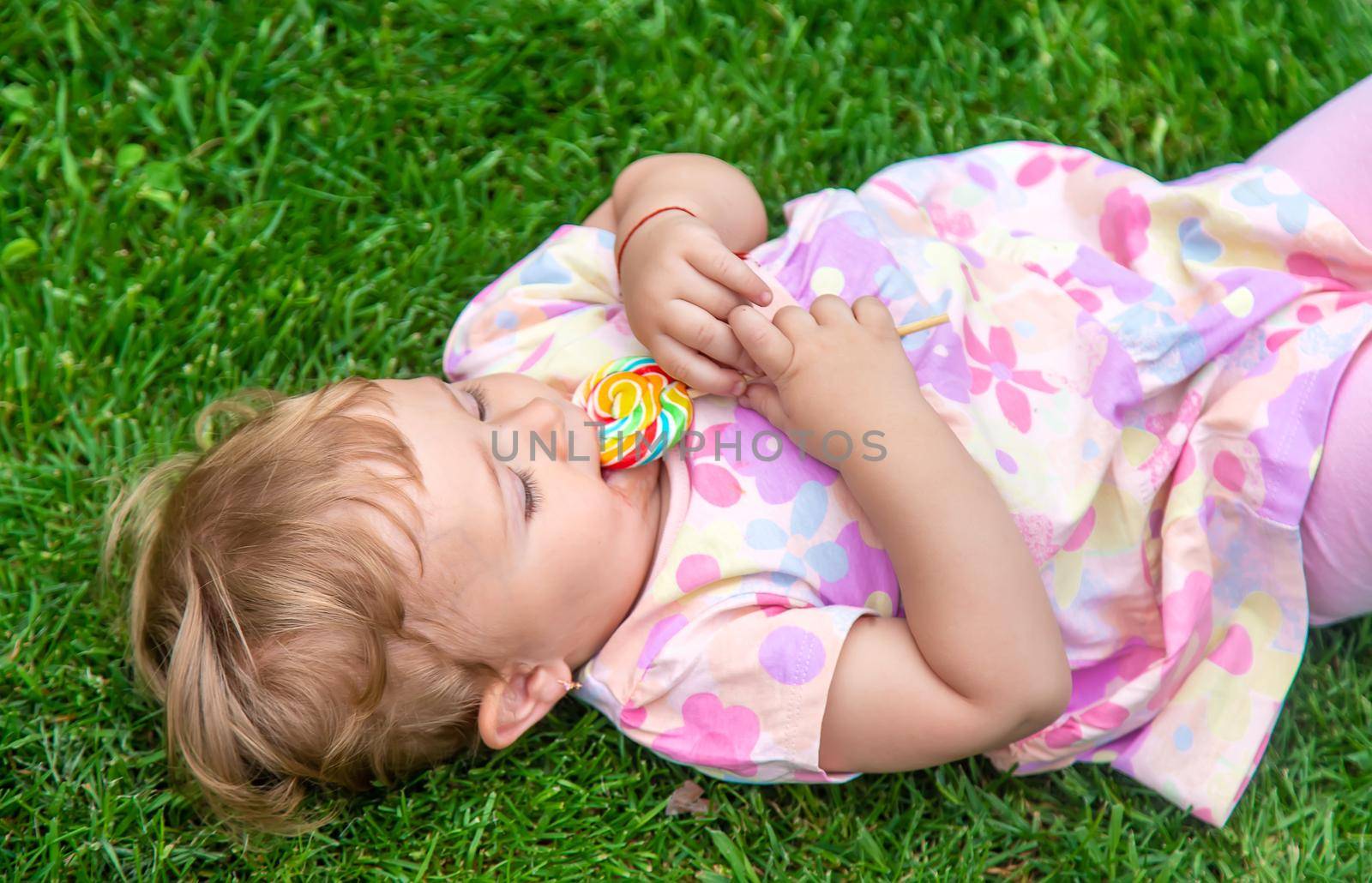 Baby eats a lollipop in the park. Selective focus. Child.