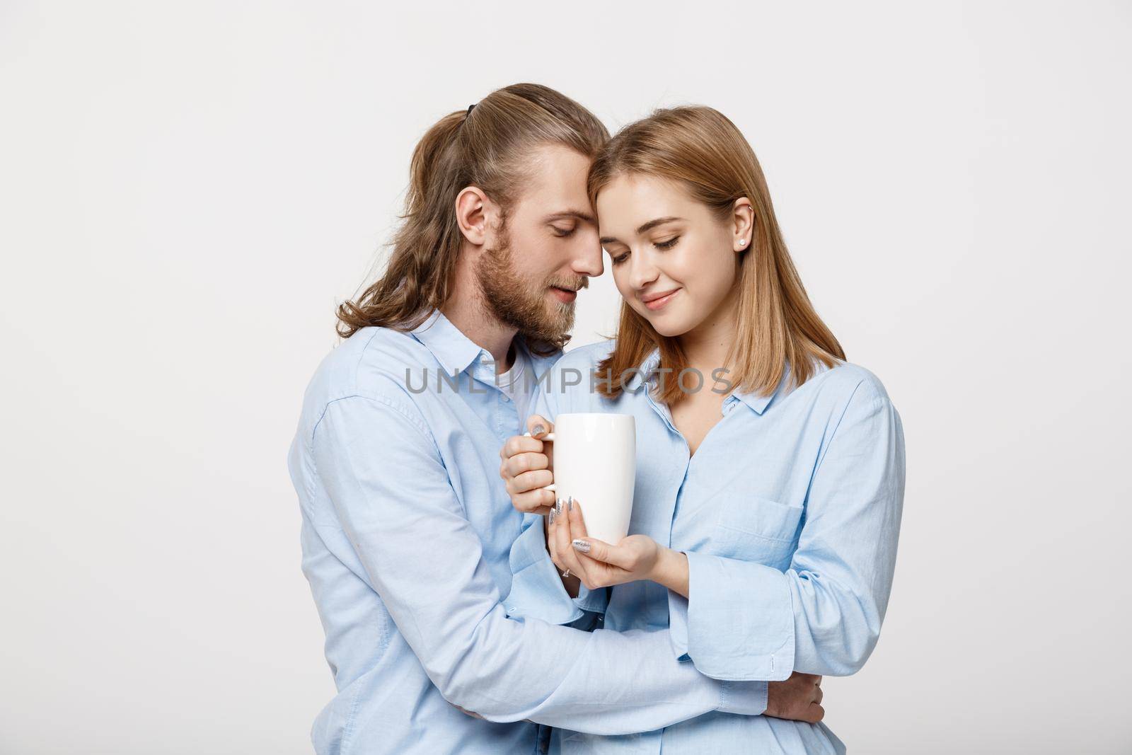 Portrait of cute young caucasian couple relaxing together huging and enjoying hot coffee .