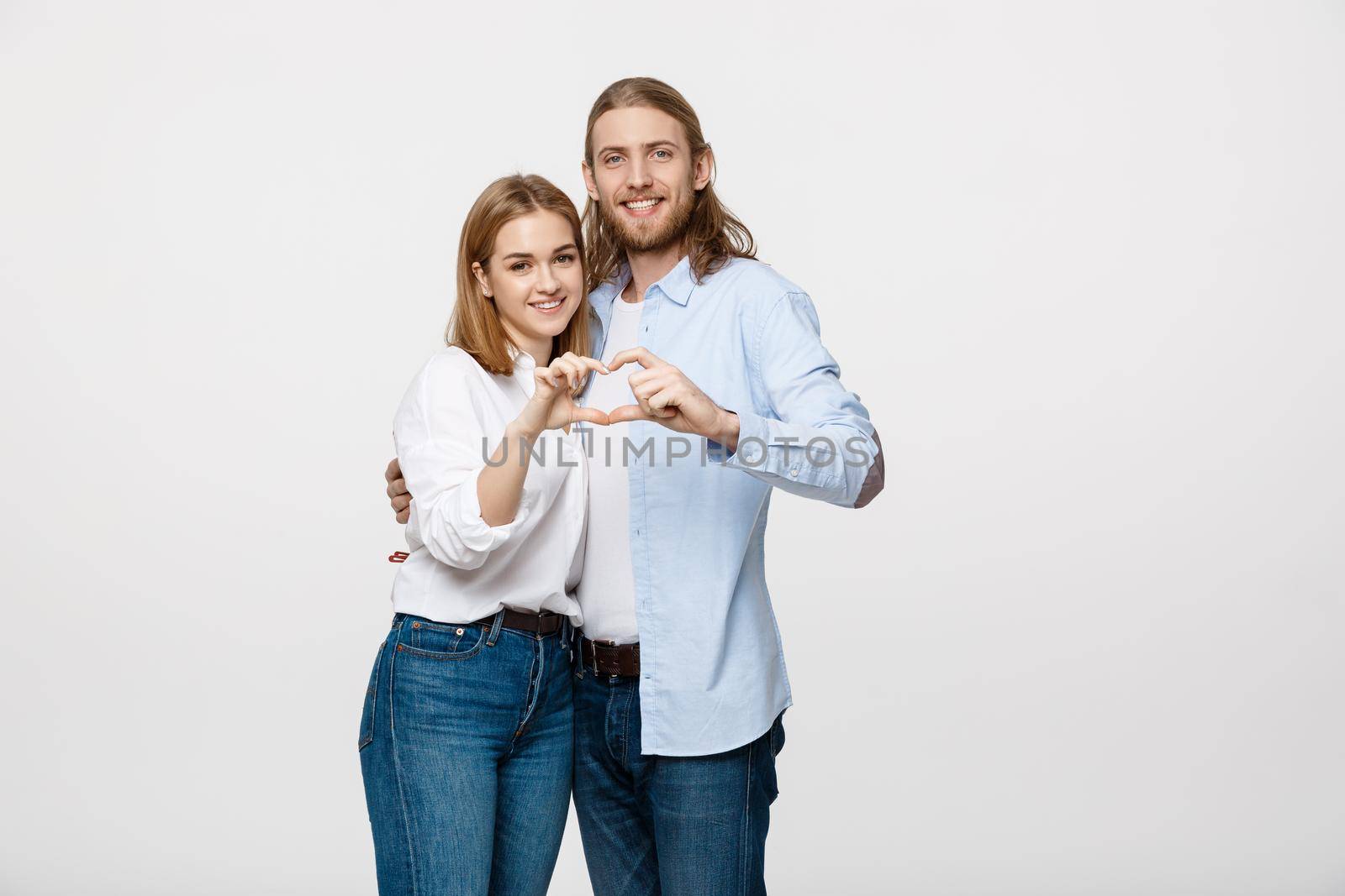 Valentine Couple - portrait of smiling Beauty Girl and her Handsome Boyfriend making shape of Heart by their Hands