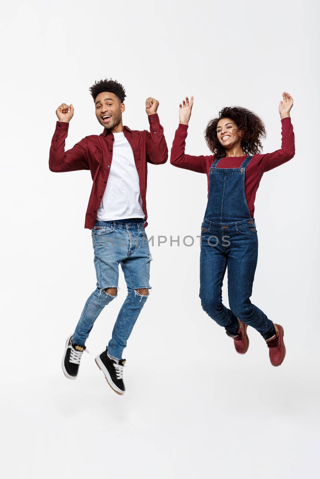 Lifestyle ,happiness and people concept: Happy young lovely African American couple jumping over bright grey background. by Benzoix