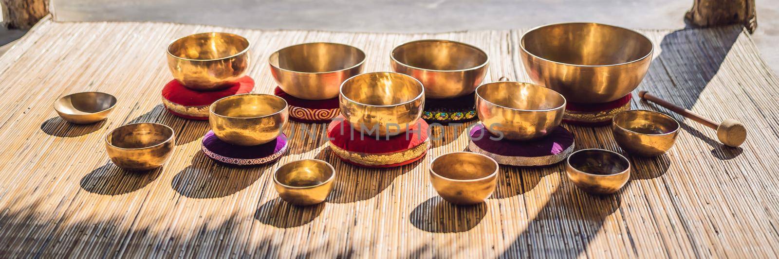 Tibetan singing bowls on a straw mat against a waterfall. BANNER, LONG FORMAT