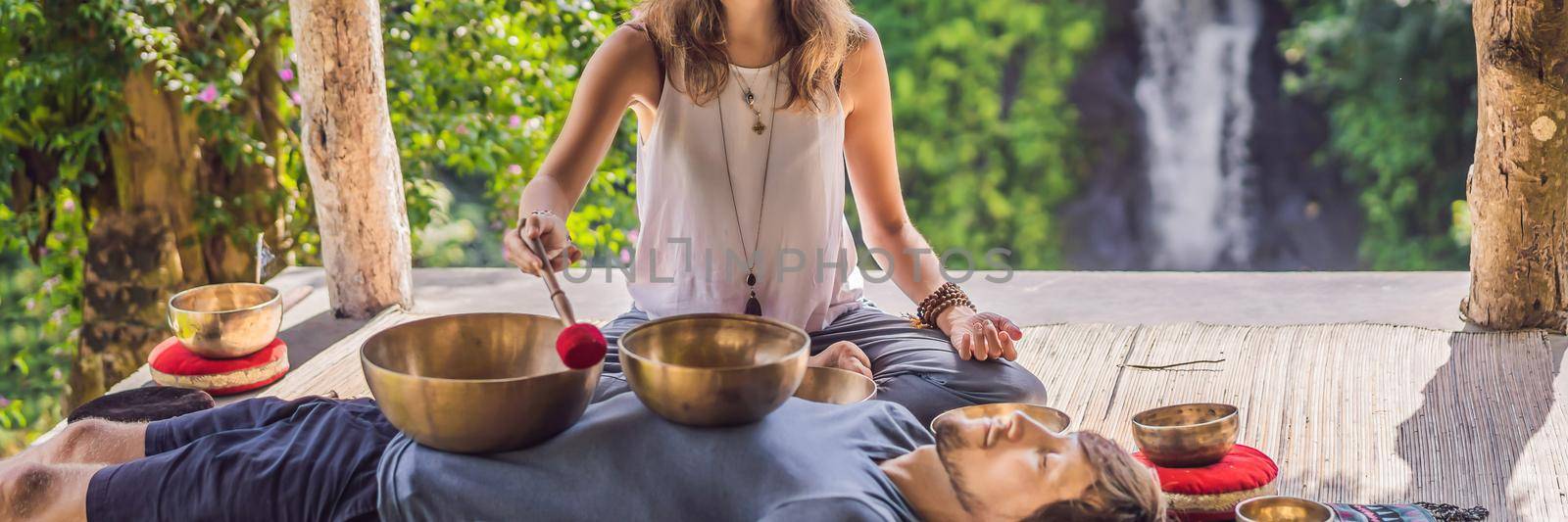 BANNER, LONG FORMAT Nepal Buddha copper singing bowl at spa salon. Young beautiful man doing massage therapy singing bowls in the Spa against a waterfall. Sound therapy, recreation, meditation, healthy lifestyle and body care concept by galitskaya