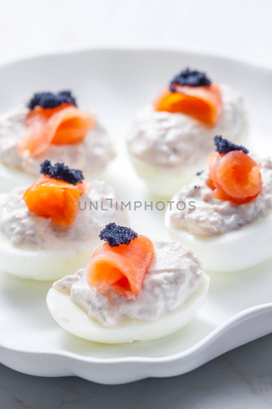 boiled eggs filled with tuna fish spread and smoked salmon and  black caviar on the top