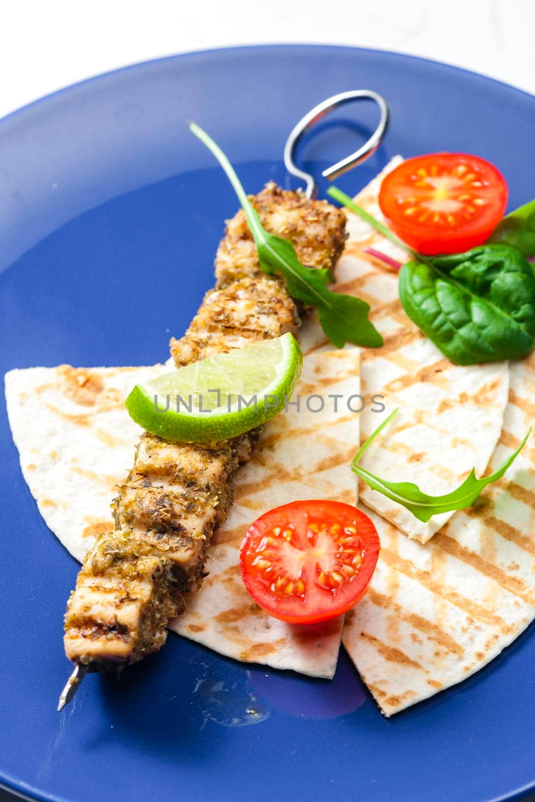herbal meat skewer  with pita bread, tomatoes and lime