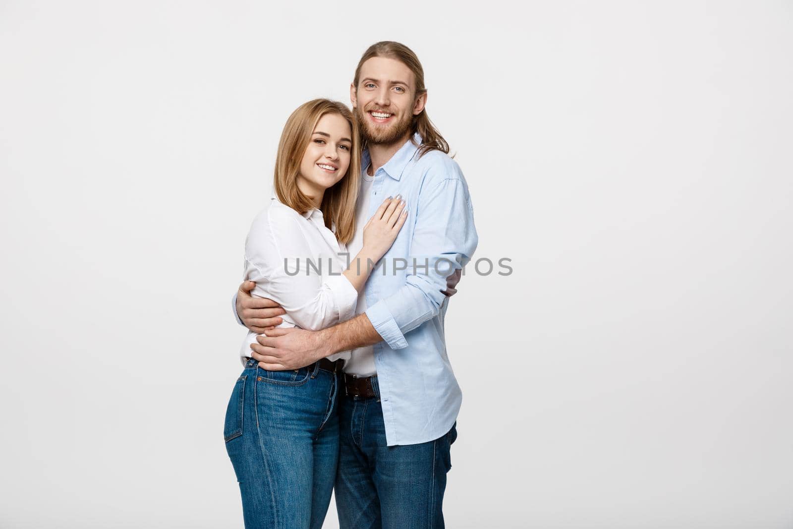 Portrait of cheerful young couple standing and hugging each other on isolated white background.
