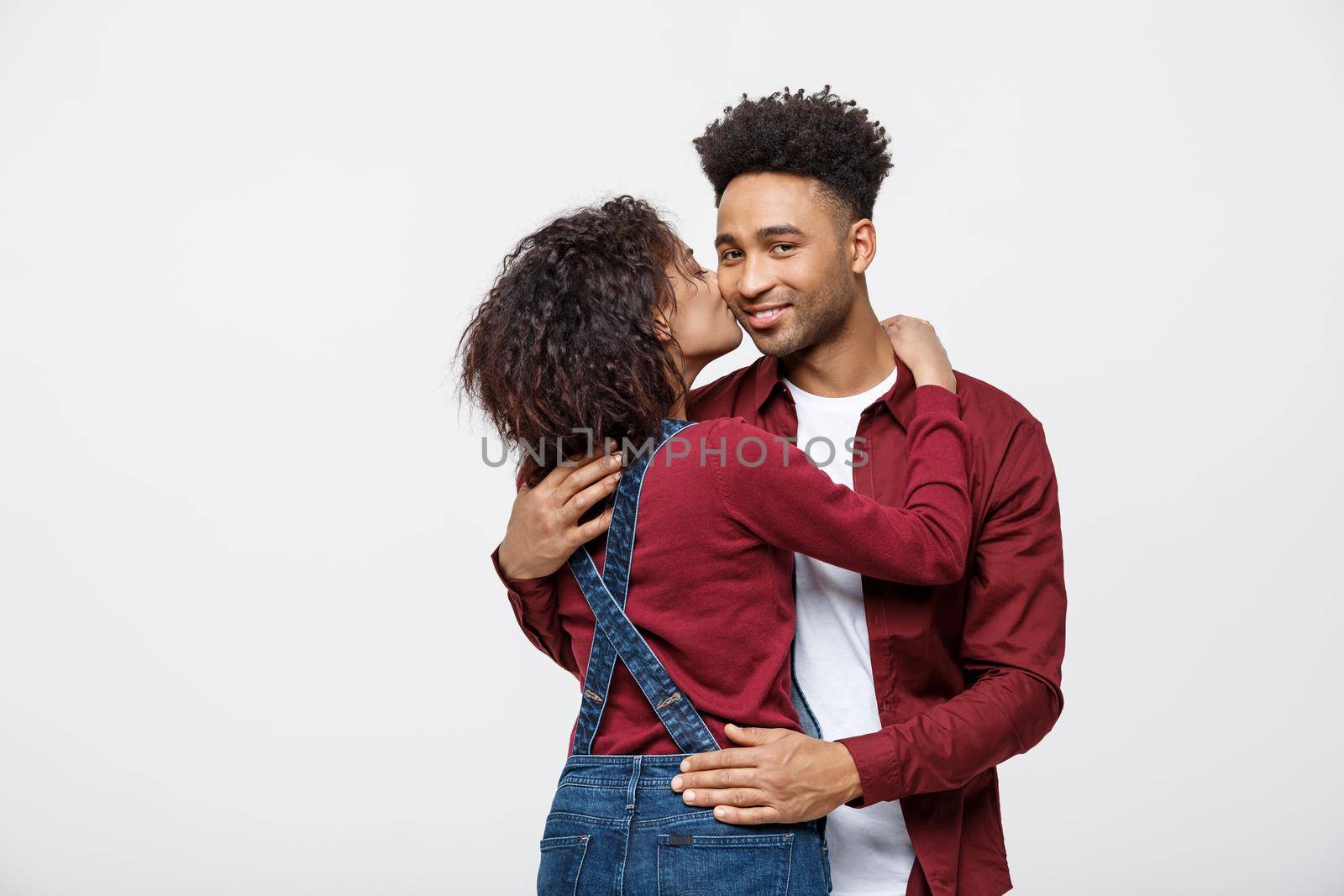 Close-up of African American young couple kissing over white background studio.