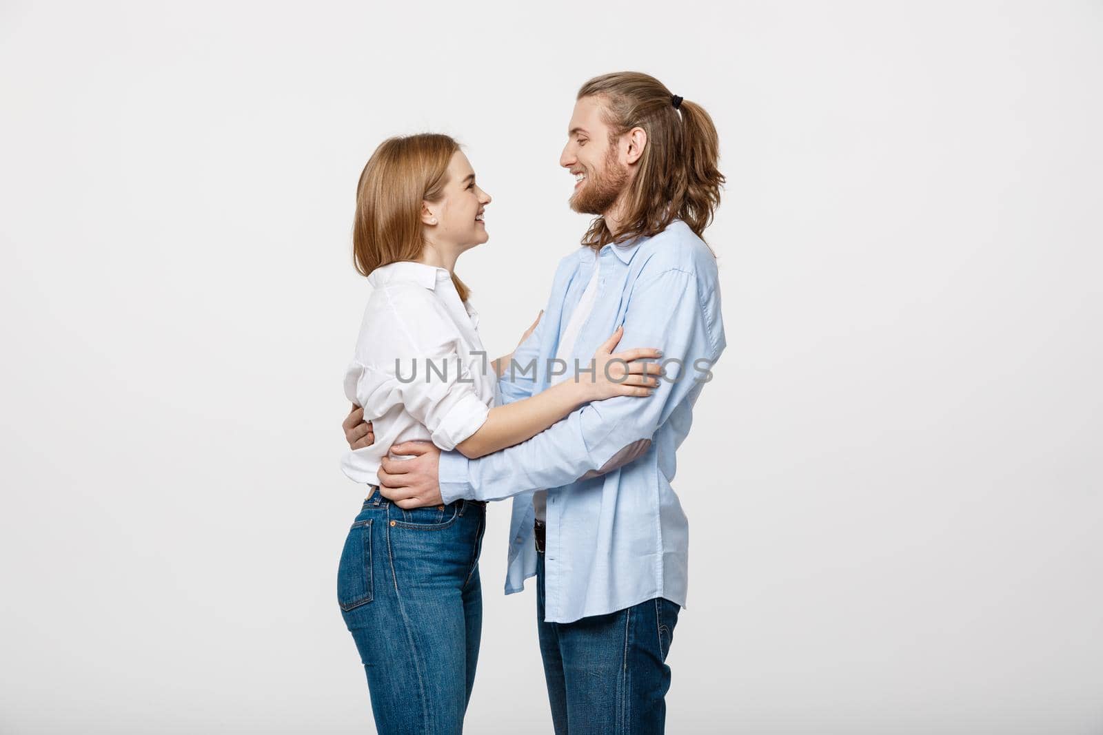 Portrait of cheerful young couple standing and hugging each other on isolated white background by Benzoix