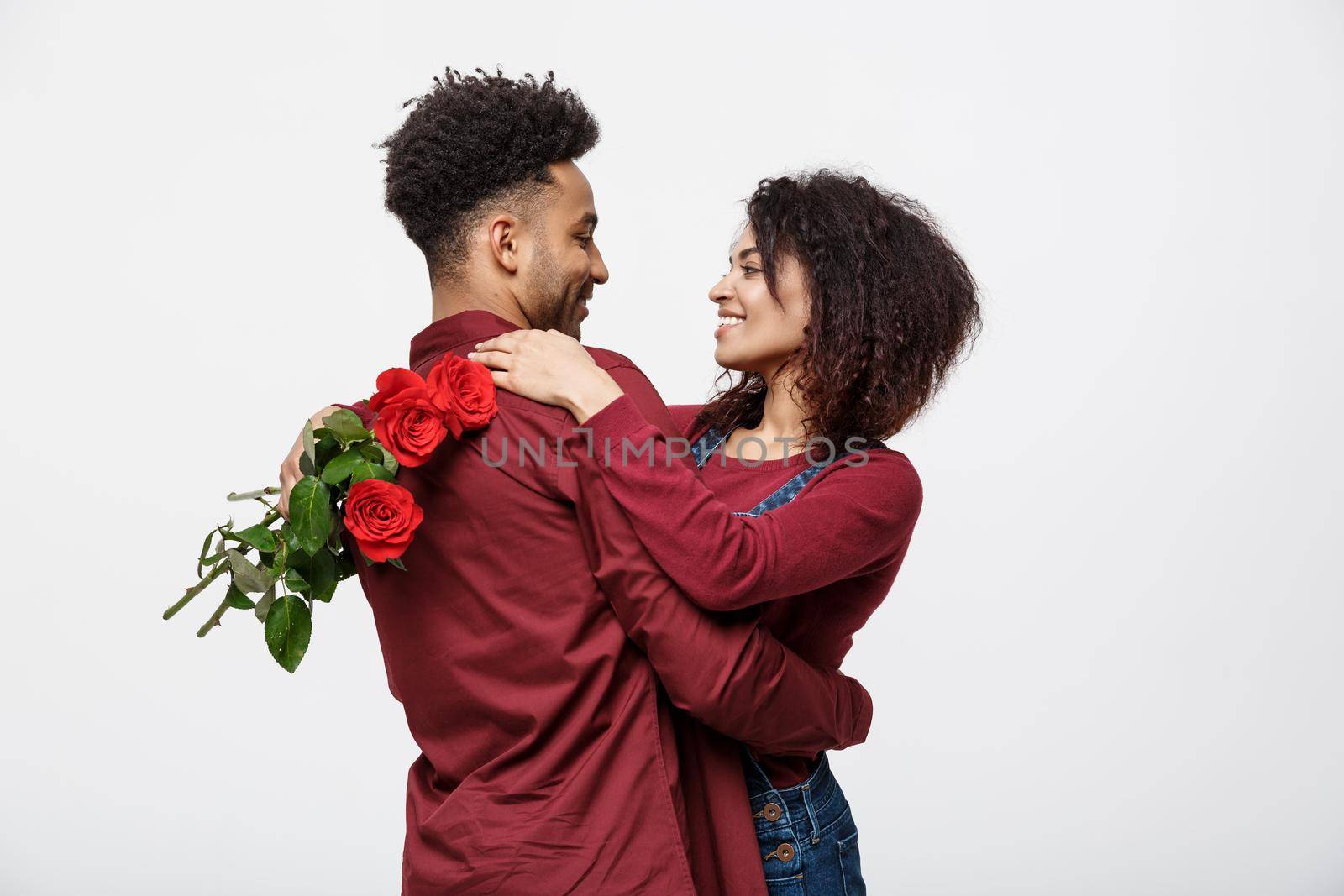 Couple Concept - Young african american couple huging each other and holding romantic red rose