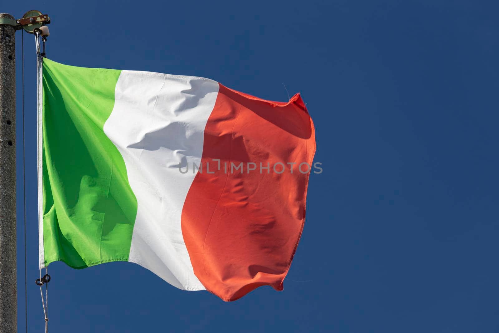 Italian flag blowing in the wind in the blue sky