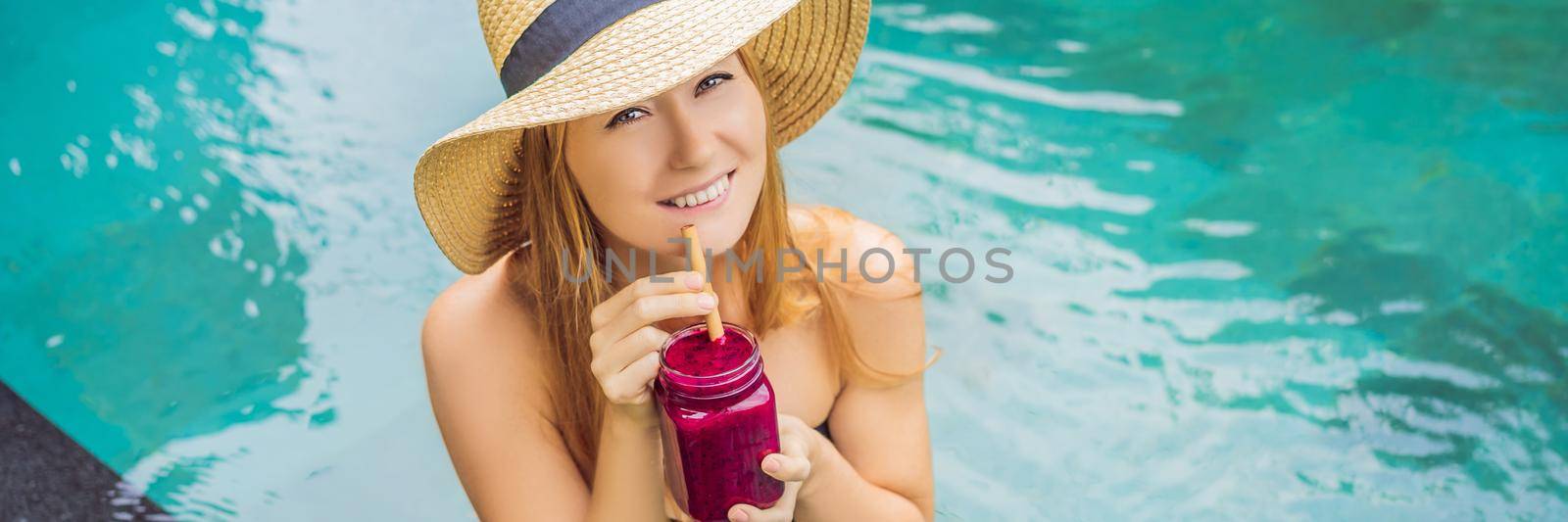 BANNER, LONG FORMAT Young woman drinking Dragon fruit smoothies on the background of the pool. Fruit smoothie - healthy eating concept. Close up of detox smoothie with Dragon fruit.