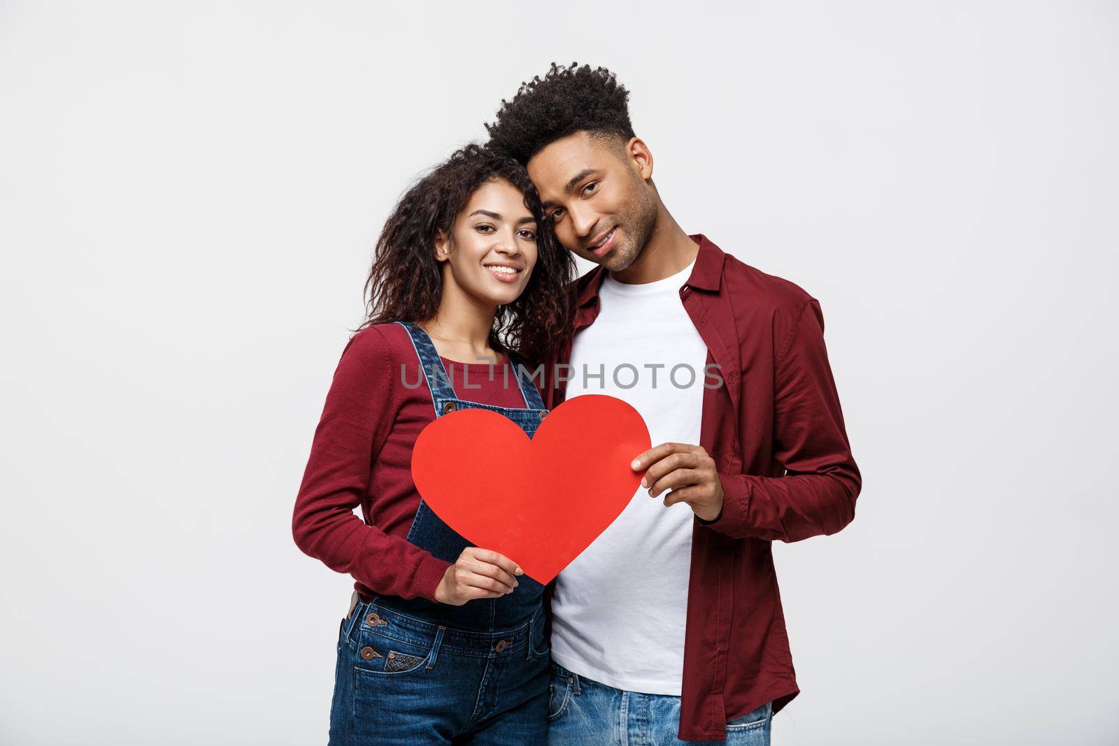 Young happy African American couple in love holding red paper heart. by Benzoix