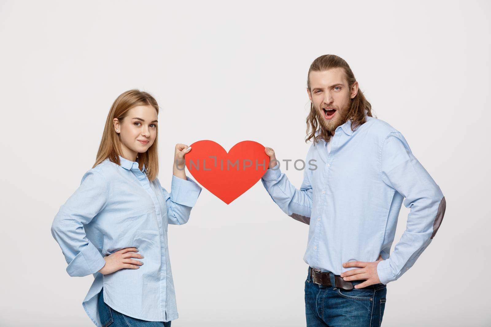 Portrait of young happy couple in love holding red paper heart. by Benzoix