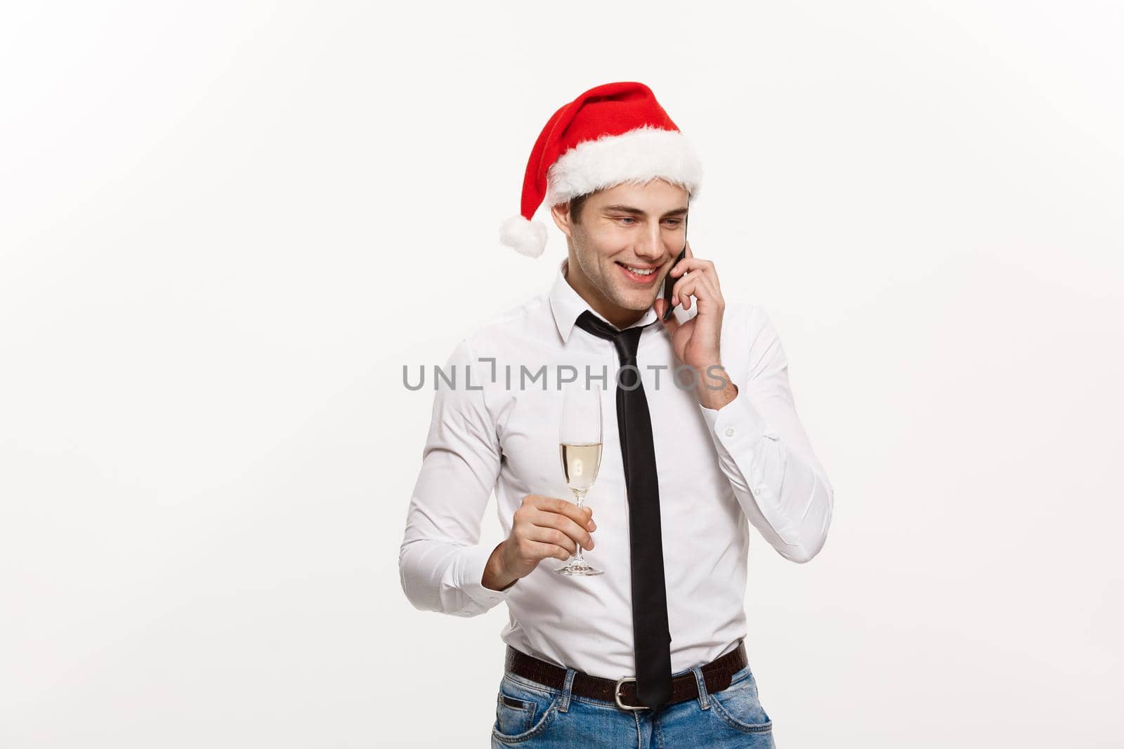 Christmas Concept - Handsome Business man talking on phone and holding glass of champange celebrating Chirstmas and New year.
