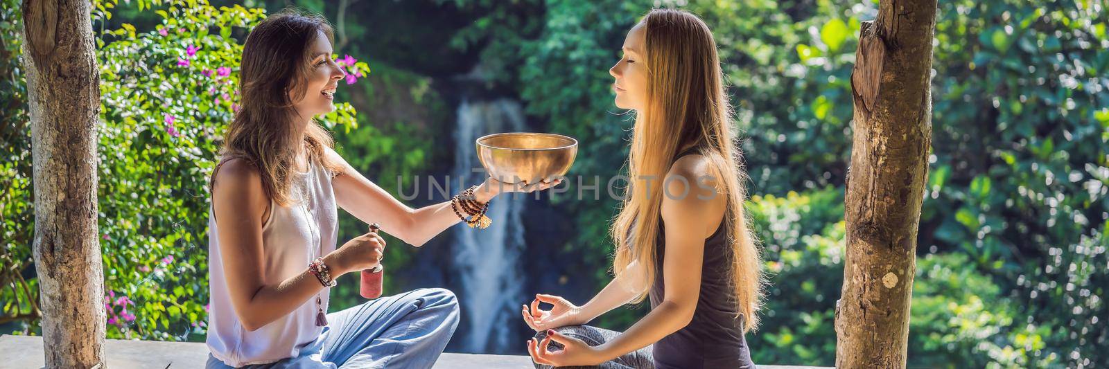BANNER, LONG FORMAT Nepal Buddha copper singing bowl at spa salon. Young beautiful woman doing massage therapy singing bowls in the Spa against a waterfall. Sound therapy, recreation, meditation, healthy lifestyle and body care concept.