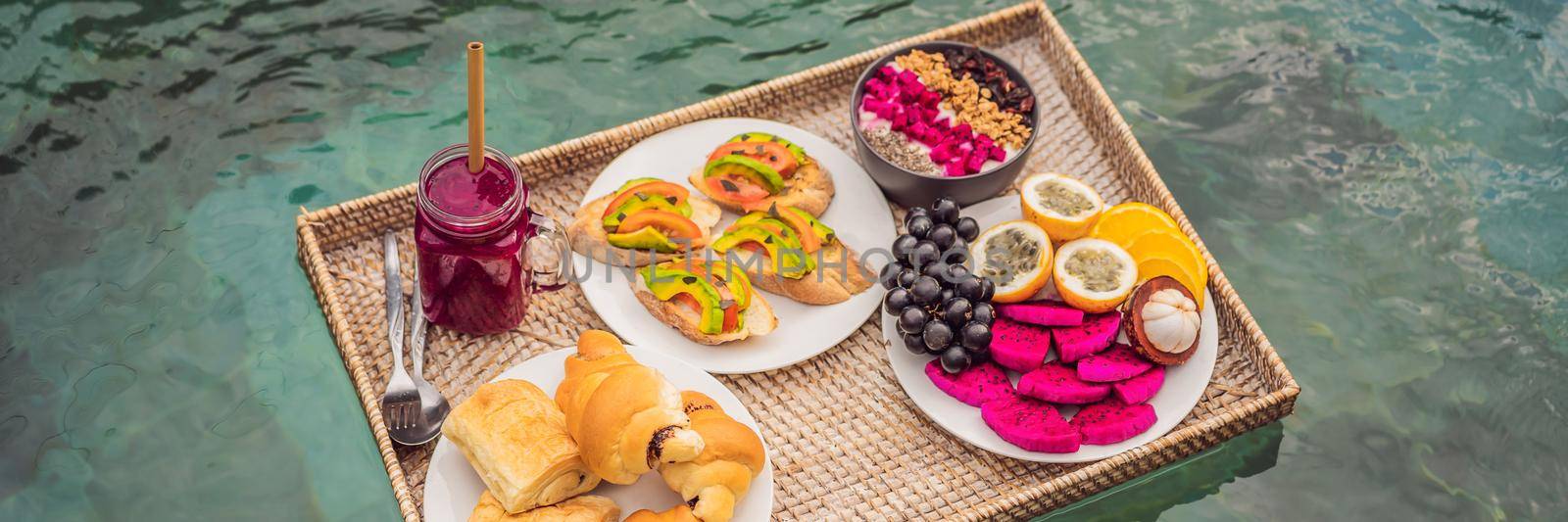 BANNER, LONG FORMAT Breakfast tray in swimming pool, floating breakfast in luxury hotel smoothies and fruit plate, smoothie bowl by the hotel pool. Exotic summer diet. Tropical beach lifestyle. Bali Trend by galitskaya