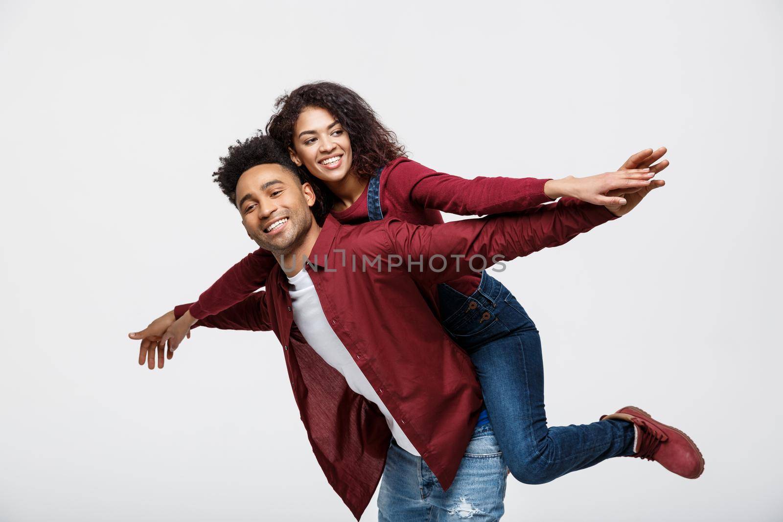 Close-up young african american couple riding back and playing like plane