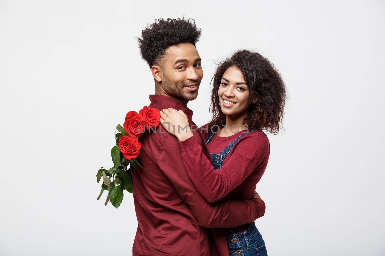 Couple Concept - Young african american couple huging each other and holding romantic red rose. by Benzoix