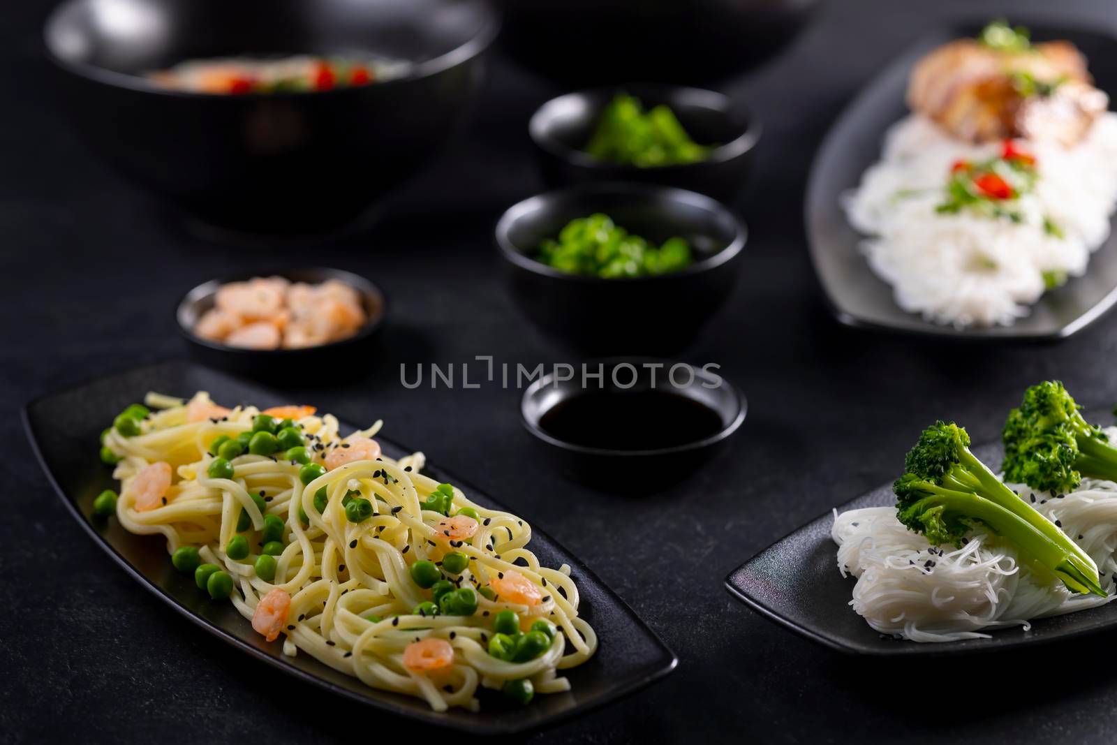 Various dishes of Asian cuisine with different types noodles and rice with shrimp, vegetables and black sesame