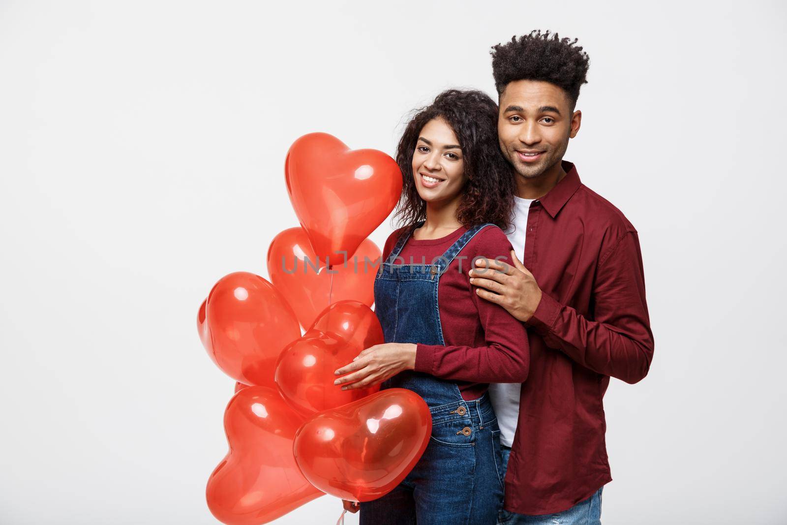 Close up attractive African American couple huging and holding red heart balloon