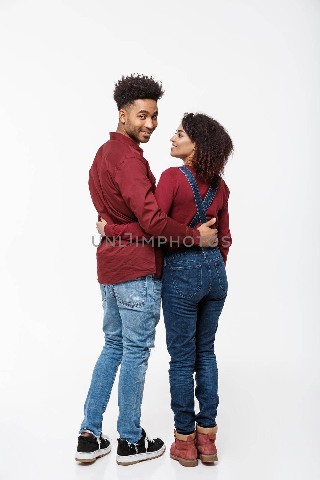 Full lenght back view of young African American couple hugging together isolated on white background.