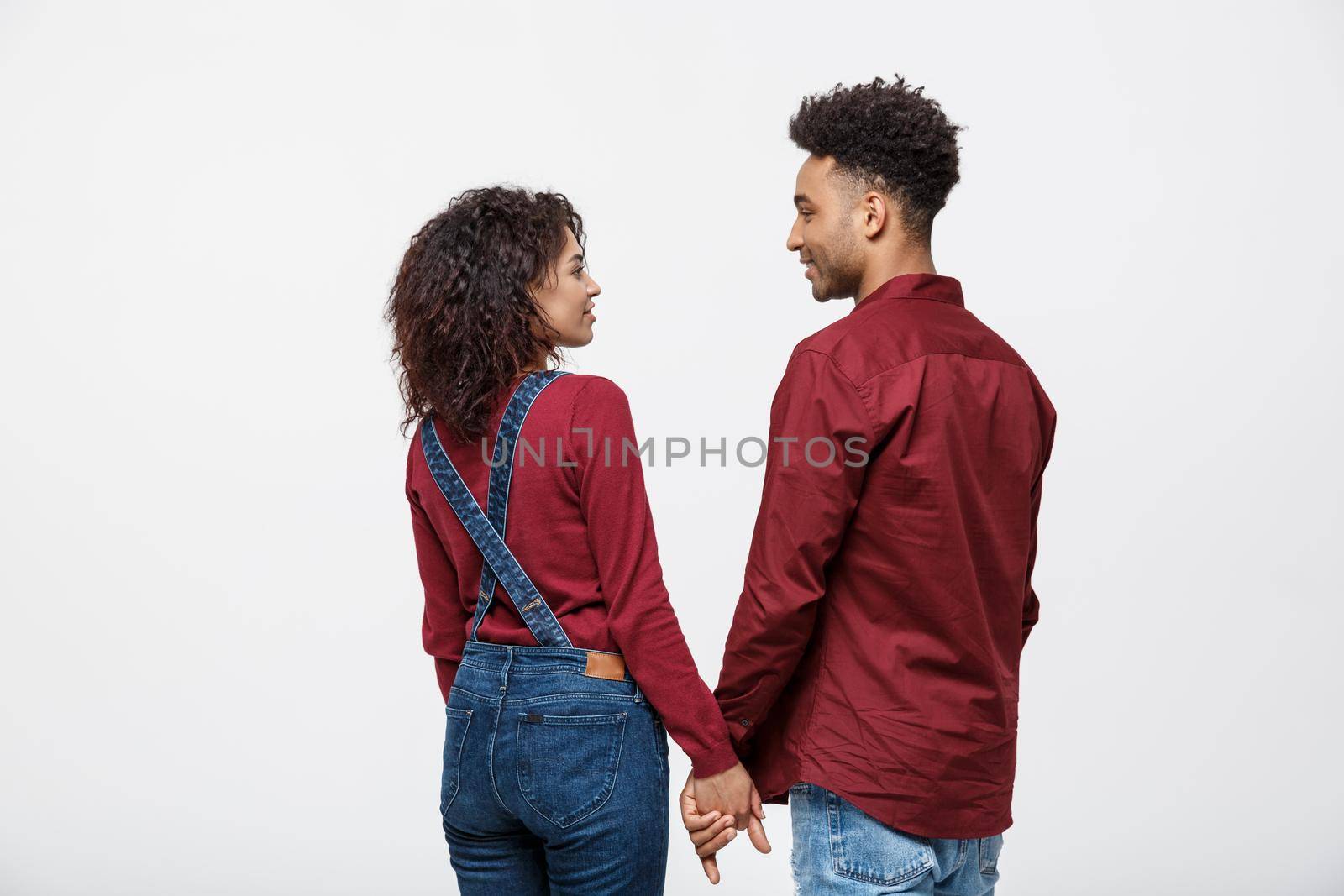 Portrait rear view of young afro american couple holding hands isolated on white background by Benzoix