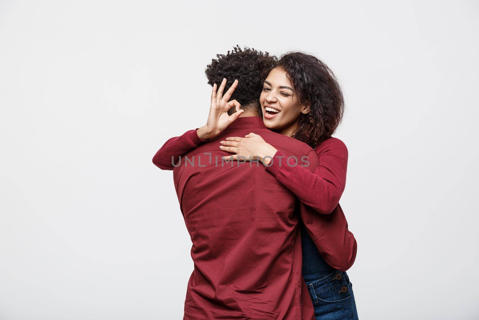 Portrait of a cheerful young african couple standing together and showing ok gesture isolated over white background.