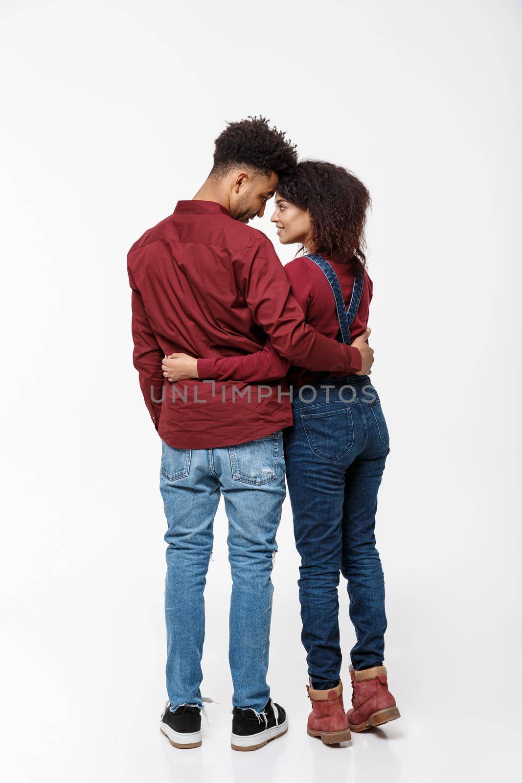 Full lenght back view of young African American couple hugging together isolated on white background.