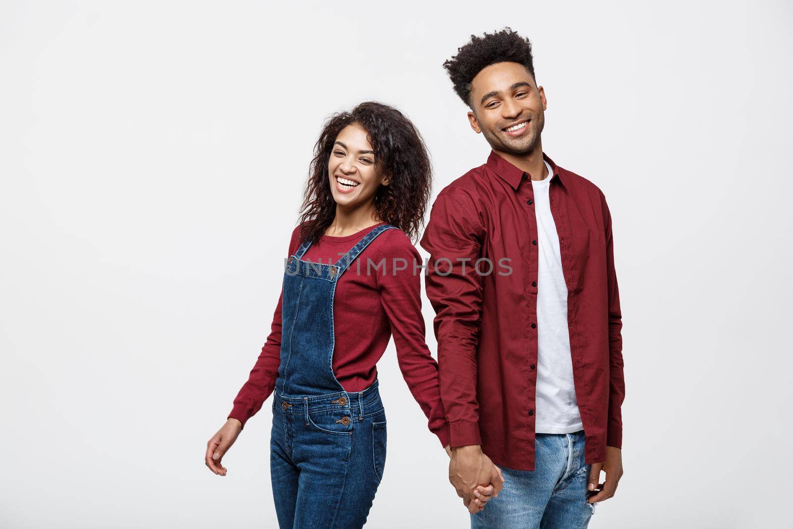 happy african american couple holding hands and looking back isolated on white.