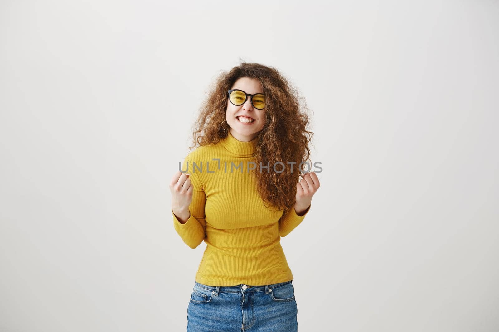 Portrait of a joyful happy teenage girl celebrating success while dancing isolated over gray background