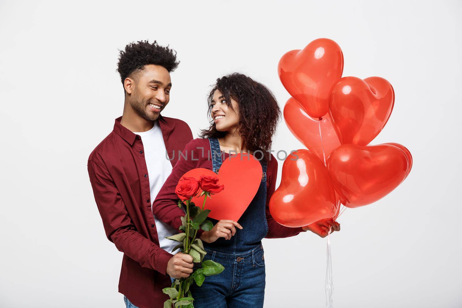 Young attractive african american couple on dating with red rose,heart and balloon