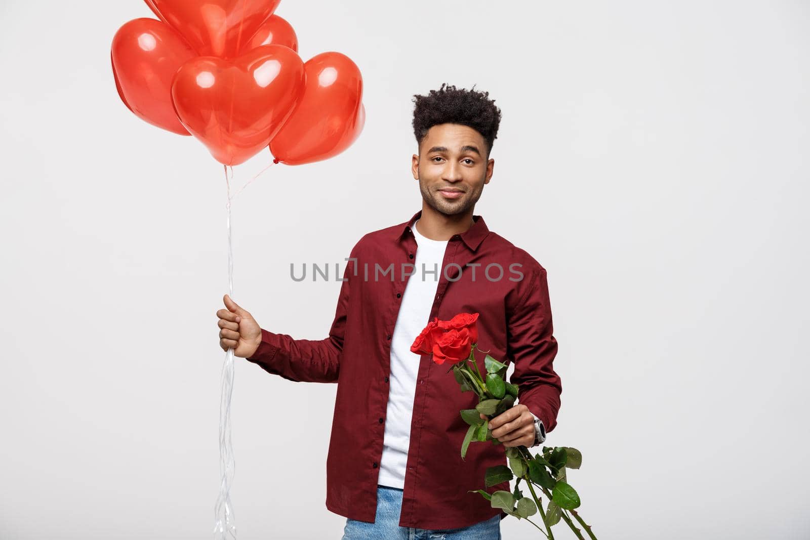 Young attractive man holding red balloon and rose for surprising his girlfriend