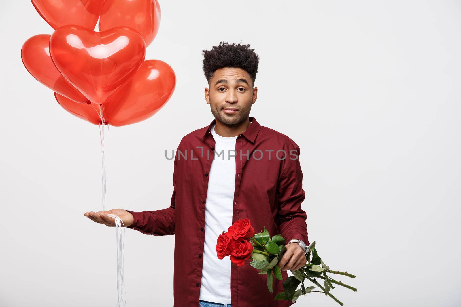Valentine's Day: African American man holding red rose and balloon with disappointed expression