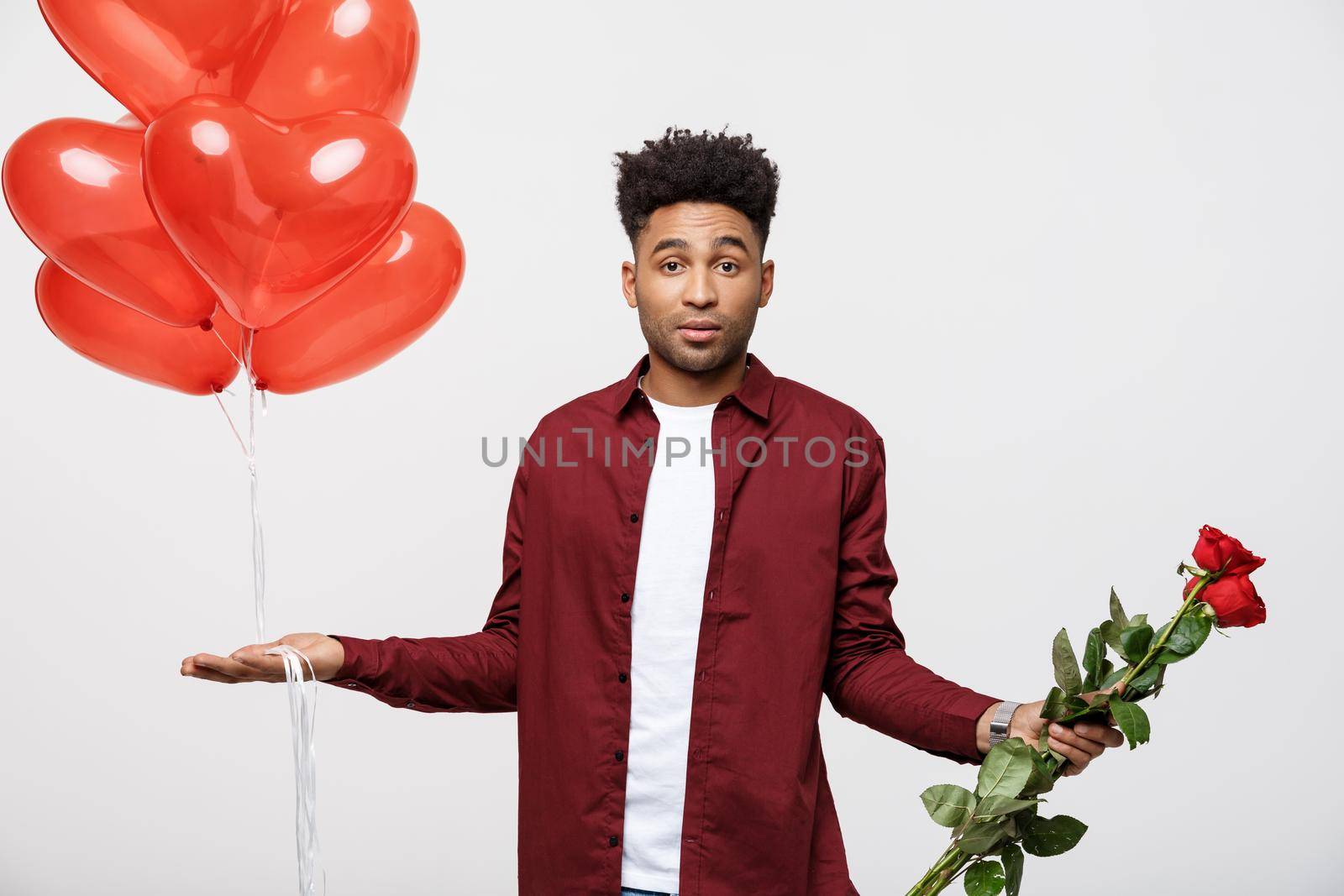 Valentine's Day: African American man holding red rose and balloon with disappointed expression