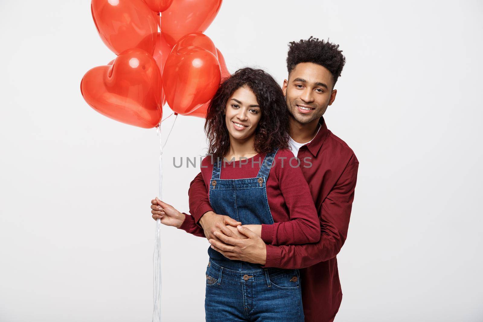 Close up attractive African American couple huging and holding red heart balloon