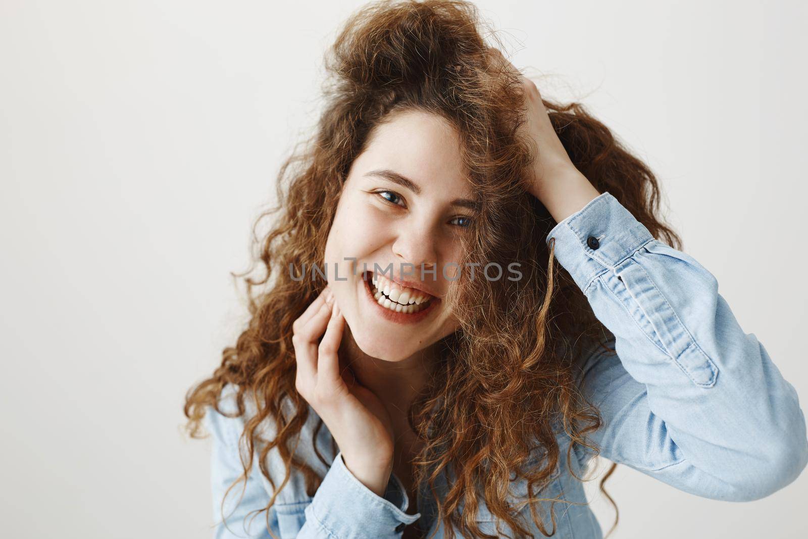 Portrait beautiful woman face close up portrait young curly hair studio on gray.