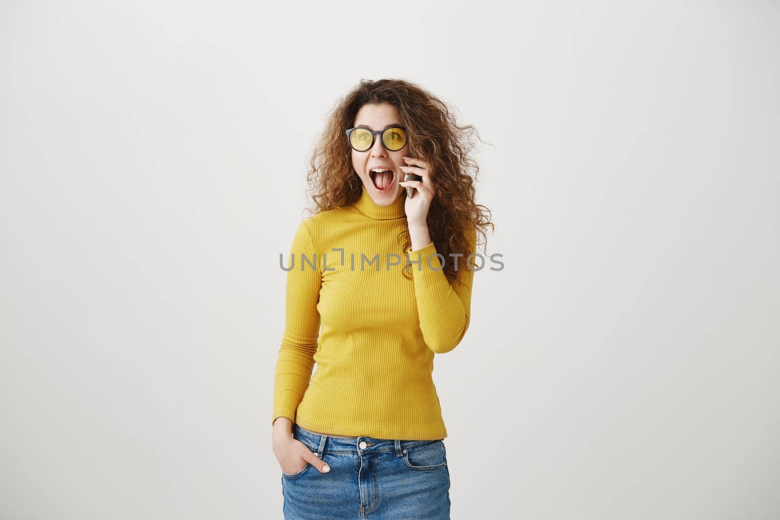 Cheerful young woman talking on mobile phone isolated on gray background