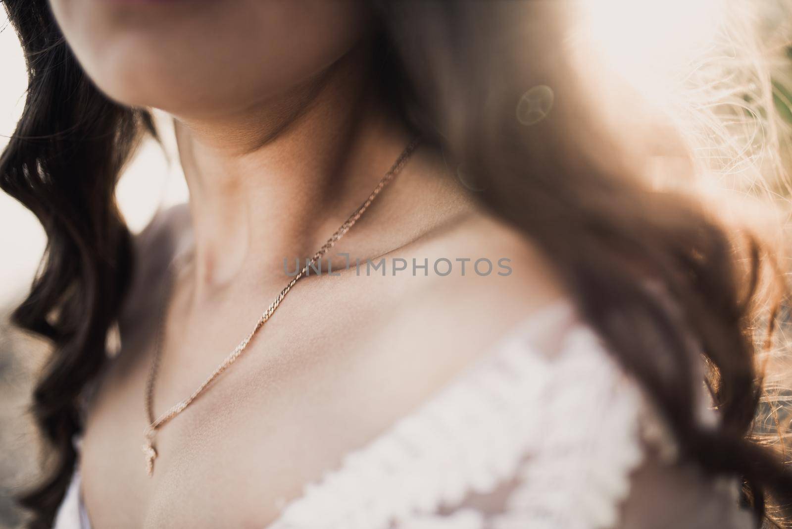 female clavicle tanned girl. Curly-haired bride in a wedding dress in the rays of the sun.