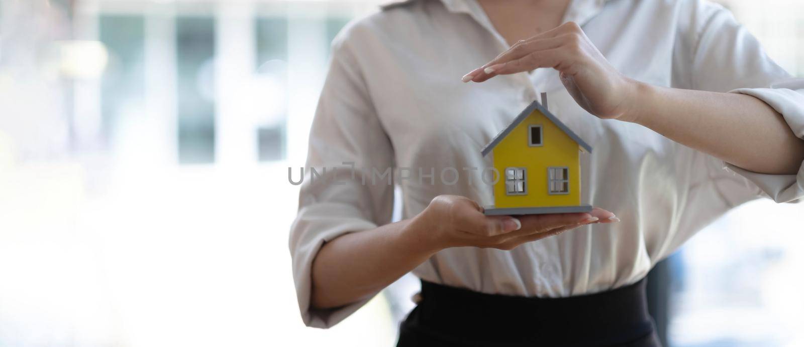 real estate agent use their hands to protect the red roofs, the concept of protecting houses using the gestures and symbols of real estate investors, taking care of credit and contracts..
