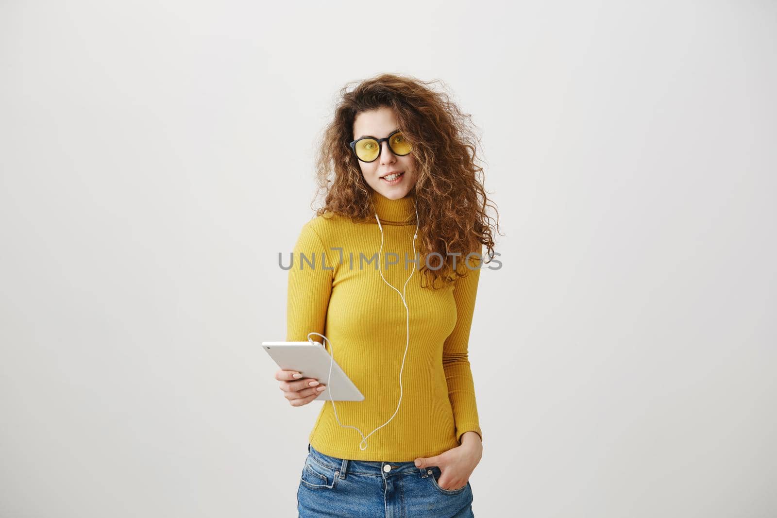 beautiful woman in headphones listening music and using digital tablet isolated on grey