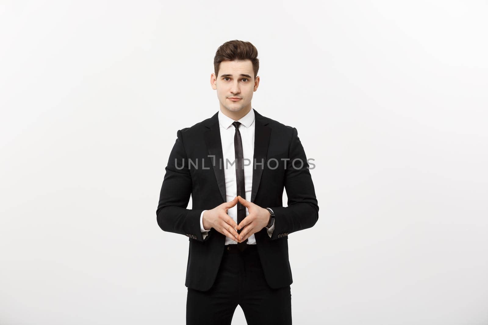 Portrait of cheerful, attractive, handsome businessman holding hands with confident face looking at camera standing over grey background.