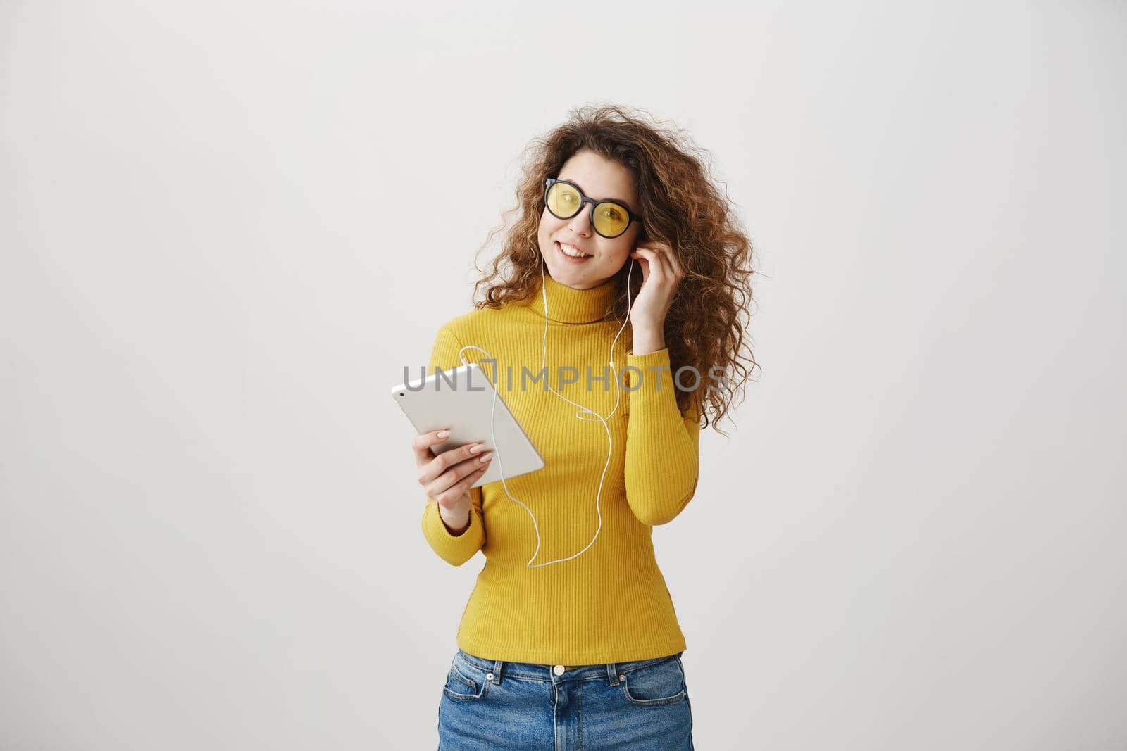 beautiful woman in headphones listening music and using digital tablet isolated on grey