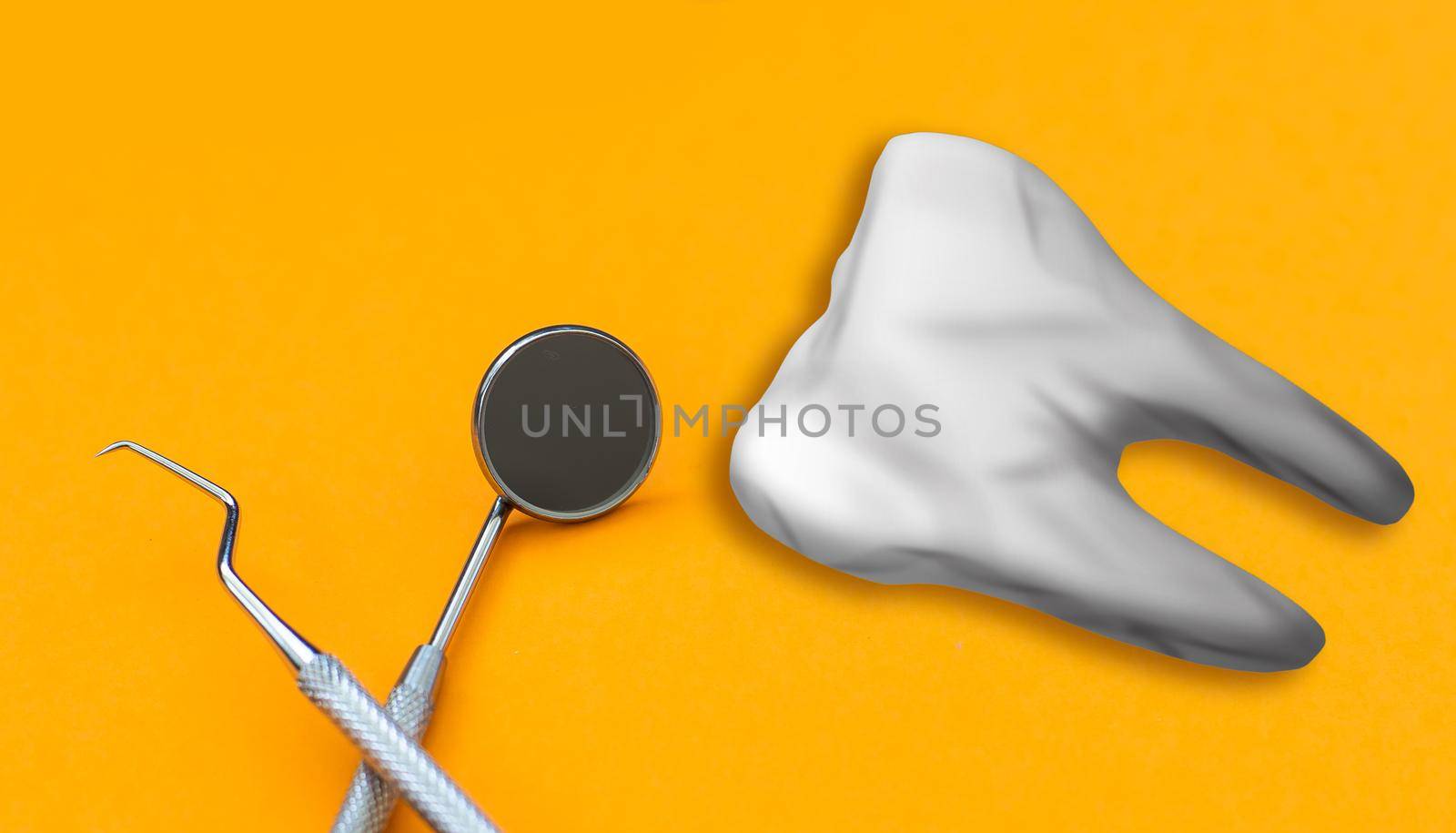 Artificial tooth and dental instrument on table. Dental services concept by Andelov13