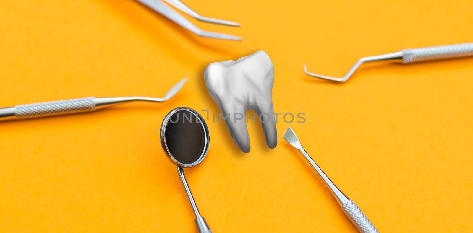 Artificial tooth and dental instrument on table. Dental services concept.