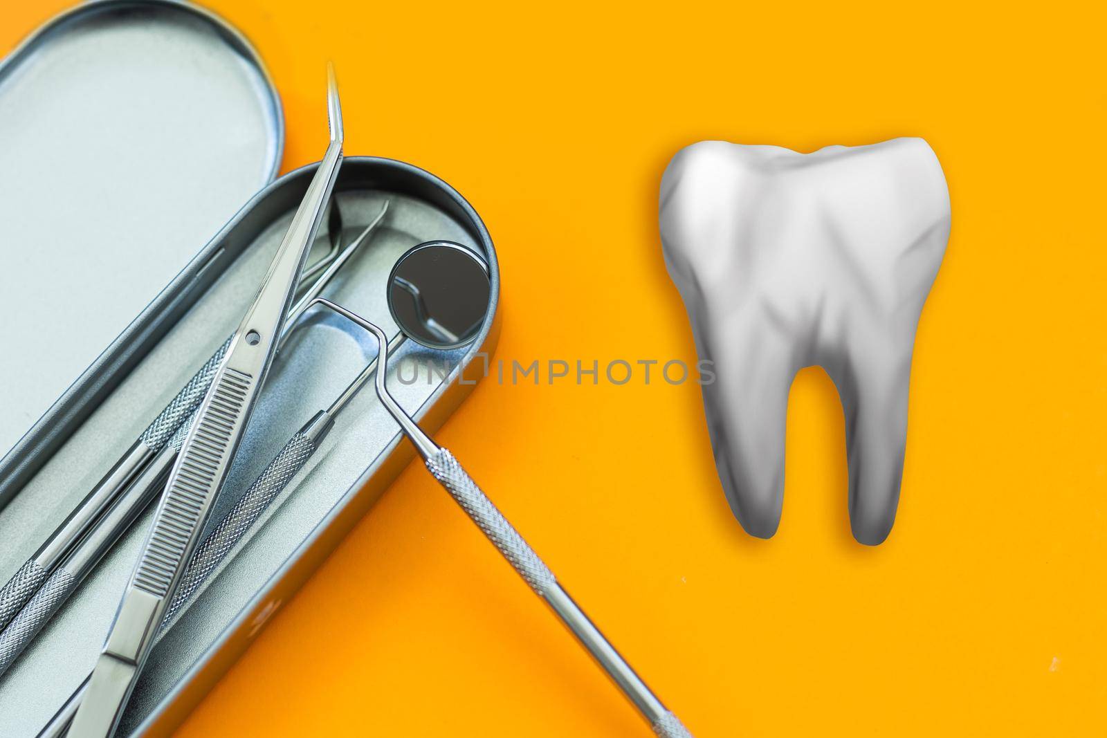 Artificial tooth and dental instrument on table. Dental services concept by Andelov13